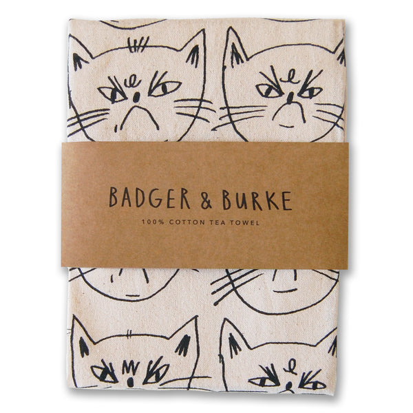 a tea towel featuring a sceenprinted illustration of snitty kitty's face multiplied. The fabric is an unbleached cotton.