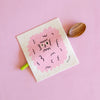 a swedish sponge cloth featuring an illustration of a pink fluffy dog face with goofy eyes.