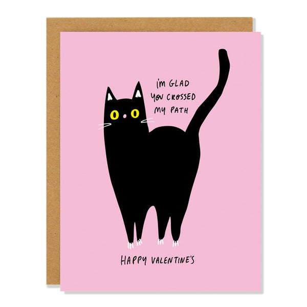 A pink Valentine's Day card featuring a black cat with yellow eyes and the text "I'm glad you crossed my path" above it and "Happy Valentine's" below it.