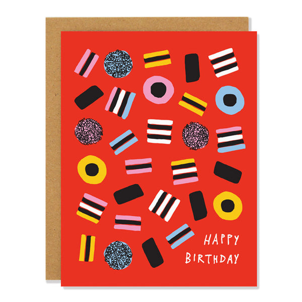 a birthday greeting card featuring an illustration of liquorice all sorts scattered across a red background. Text reads: "Happy Birthday"
