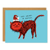 A holiday greeting card featuring an angry orange cat wearing a santa hat on a light blue background. The handwritten text above the cat reads: "Happy Holidays or Whatever..."