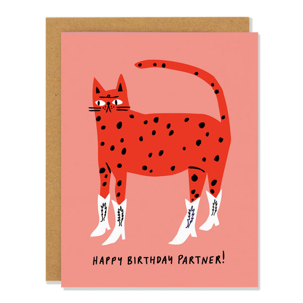 A birthday card with an illustration of a red cat with black spots and white cowboy boots, standing against a pink background, with the text "Happy Birthday Partner!" written at the bottom.