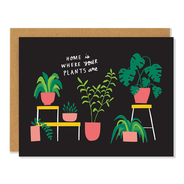 a housewarming greeting card featuring illustrations of various houseplants in terra cotta pots, including monstera, aloe, snakeplant, and palms on a black background, with text reading "home is where your plants are"