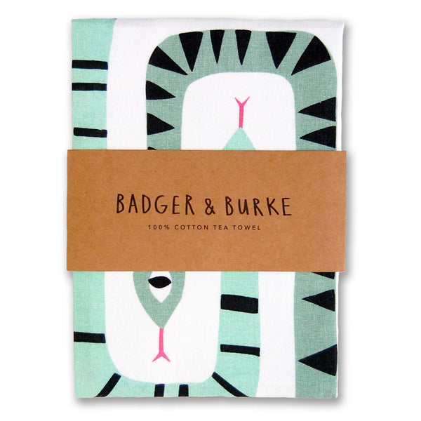 a tea towel featuring an illustration of two interwoven geometric snakes in different shades of green on white cotton.