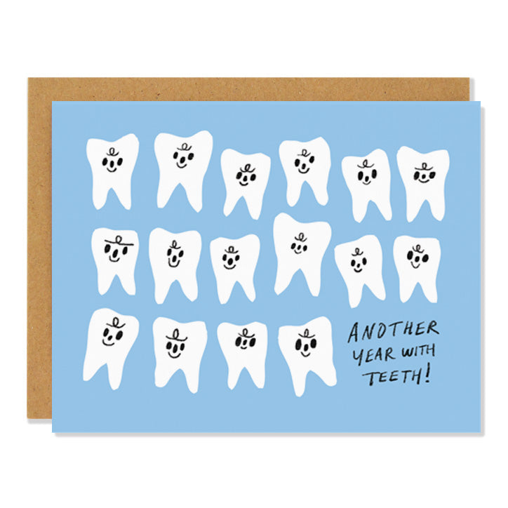 A birthday greeting card featuring an illustration of numerous human teeth with little smiling faces against a light blue background. The text in the bottom right corner reads: "Another Year with Teeth!"