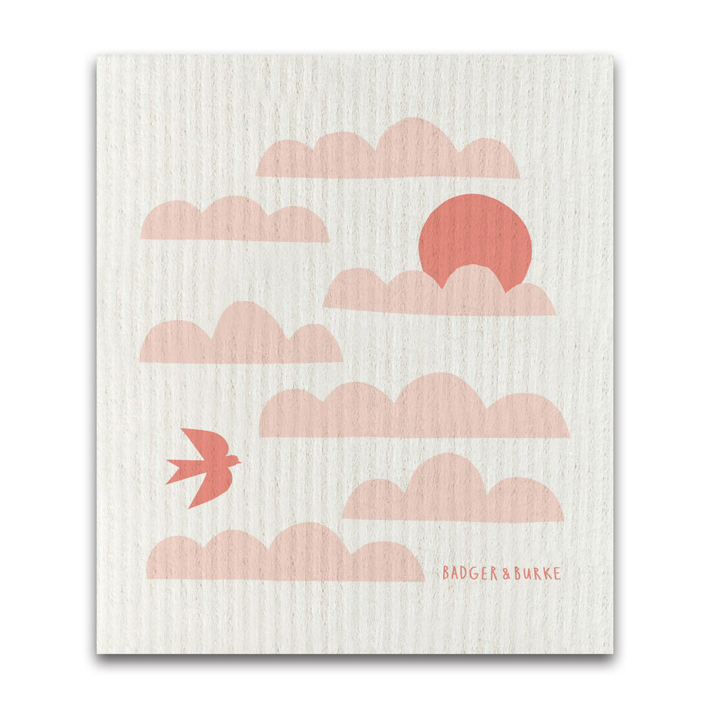 a swedish sponge cloth featuring an illustration of soft pink clouds and a red sun on a textured beige background, with a small red bird flying on the bottom