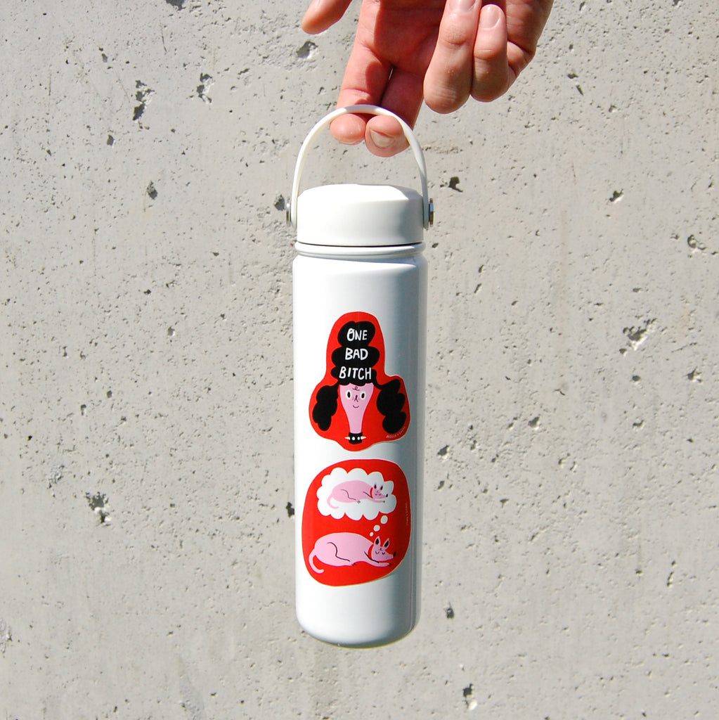 A person holding a white water bottle with a sticker with cartoon design that reads "ONE BAD BITCH" and depicts a poodle with attitude.