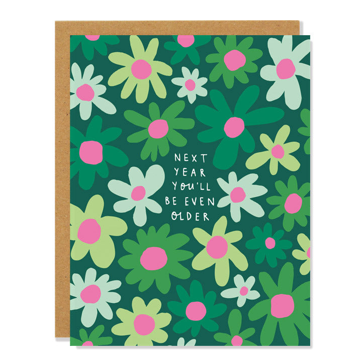 a birthday greeting card featuring an all over illustration of daisies in different shades of green with pink middles. Text reads: "next year you'll be even older".