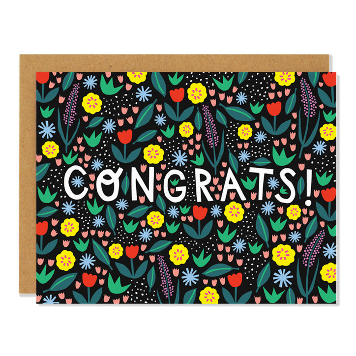 a congratulations greeting card with an all over multi coloured floral pattern on a black background, cut out letters spell out CONGRATS!