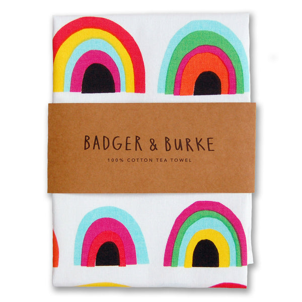 a tea towel featuring multiple cut out illustrations of rainbows in alternating colours