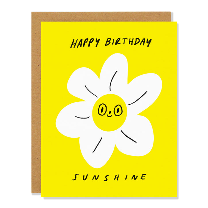 A birthday greeting card featuring an anthropomorphized daisy flower with a happy face on a sunshine yellow background. The text reads: "Happy Birthday Sunshine"
